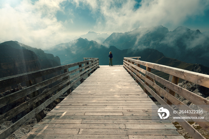 Young woman watching the mountains from boardwalk