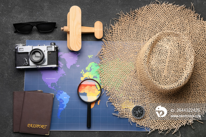 Sunglasses, wooden plane, photo camera, passports, magnifying glass, wicker hat and map on dark background