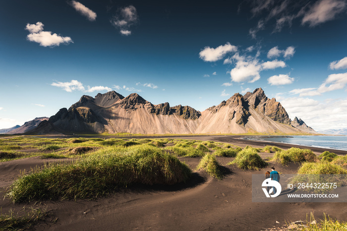 Scenery of Vestrahorn mountain and grass mound on black sand beach in sunny day at Stokksnes peninsula, Iceland