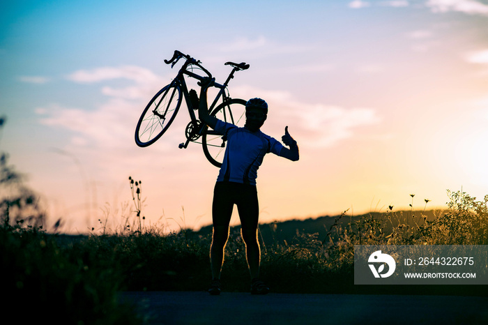 cyclist silhoutte with bicycle raised to sky race and victory concept