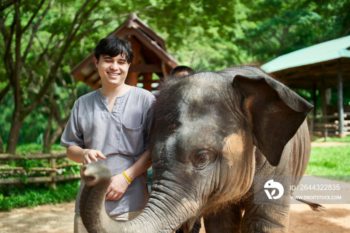 thai tourist posing with baby elephant at sanctuary