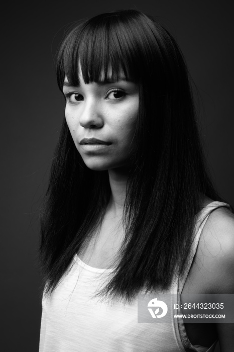 Young Asian woman against gray background in black and white