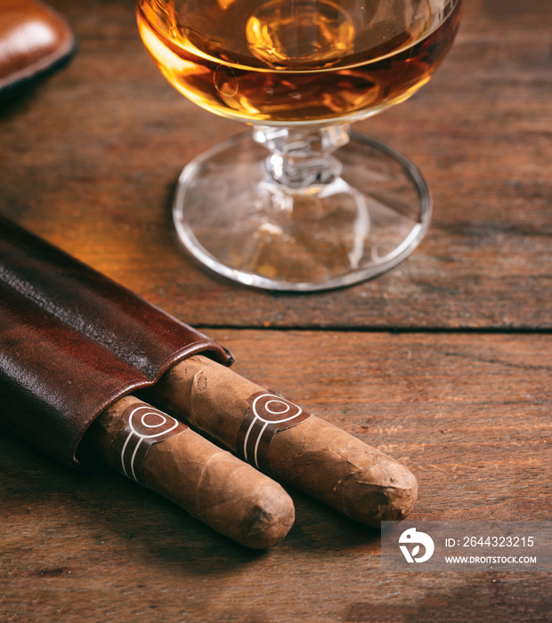 Cuban cigars and snifter with rum on wooden table