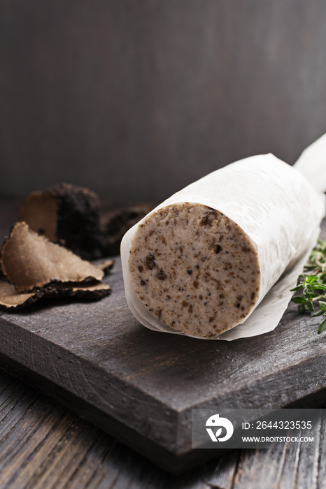 Homemade aromatic butter with black truffles on black wooden board. Selective focus.