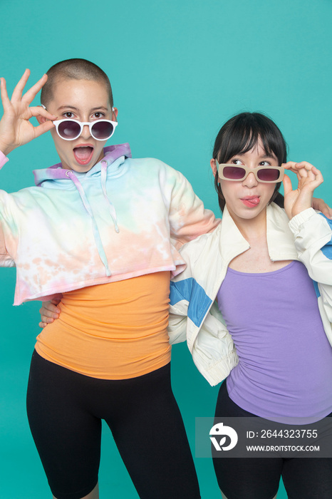 Studio portrait of two girls wearing sunglasses and making faces