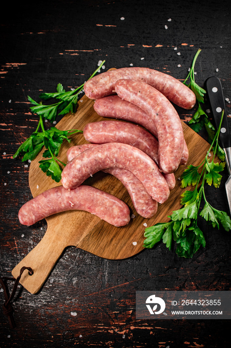 Raw sausages on a cutting board with parsley.