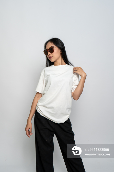 A young woman with a white blank shirt and glasses doing a cool pose on a white background