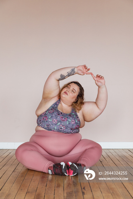 plus size woman sitting on floor stretching