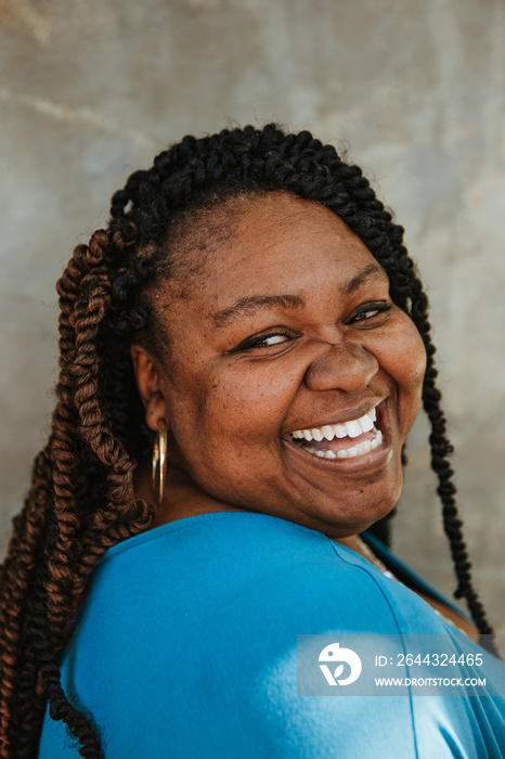 closeup portrait of a smiling plus size afro latinx haitian american woman looking over shoulder