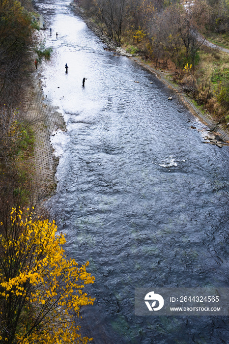 Anglers fishing for salmon in a cold river in autumn