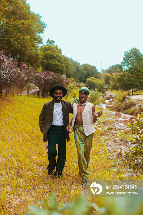 Two Malaysian Indian men surrounded by nature, walking in the grass, laughing together