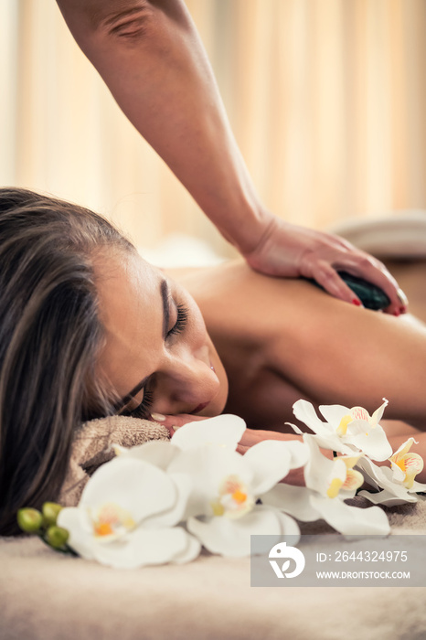 Woman enjoying the therapeutic effects of a traditional hot stone massage