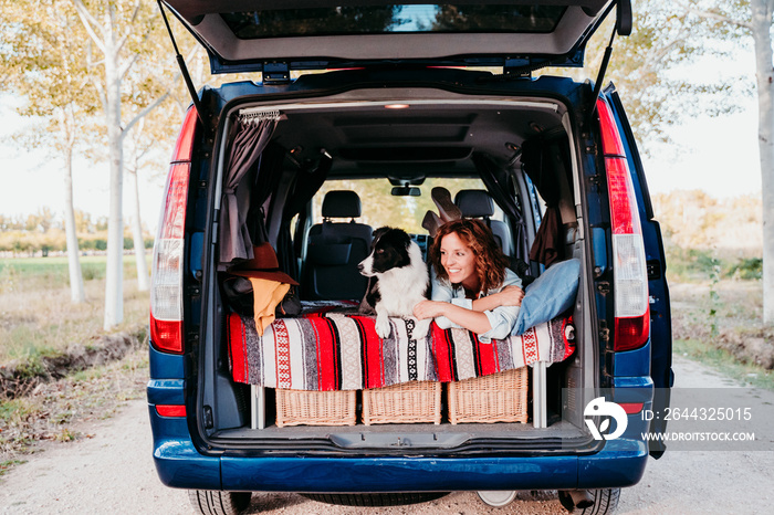 young woman and her cute border collie dog relaxing in a van. travel concept.