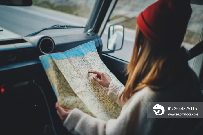 Happy traveler girl sitting in vintage car exploring map while enjoying vacation in Europe, lifestyle adventure concept, woman planning next direction during road trip