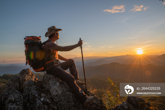 Backpacking hikers relax at the top of the mountain and enjoy views of the valley during the sunrise.