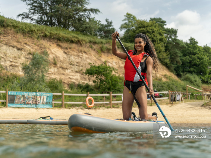 Smiling woman paddleboarding on lake