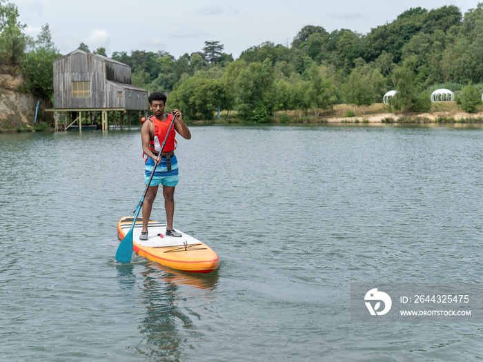 Young man paddleboarding on lake