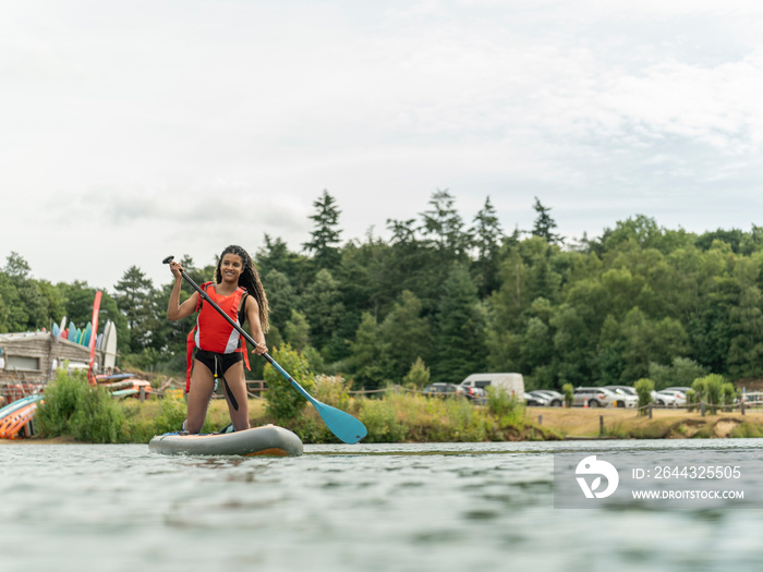 Smiling woman paddleboarding on lake