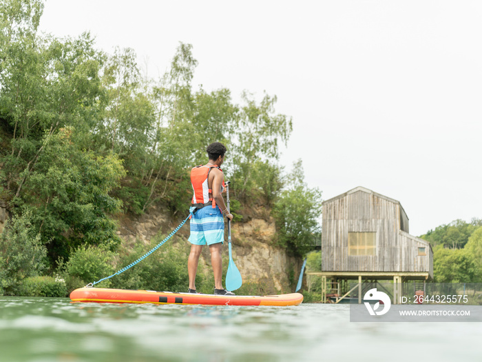 Young man paddleboarding on lake