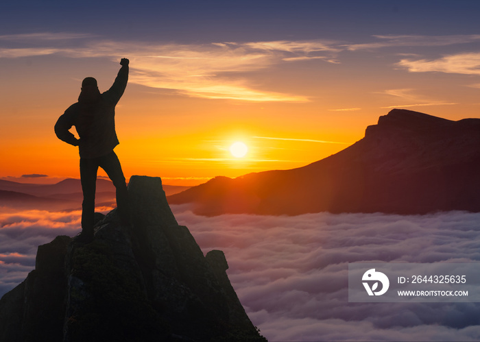 Winner man standing on a cliffs edge in a mountains