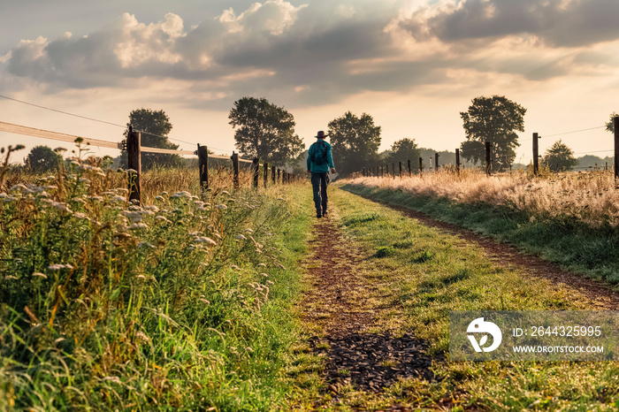 Man in hat walking alone on end of rural track.