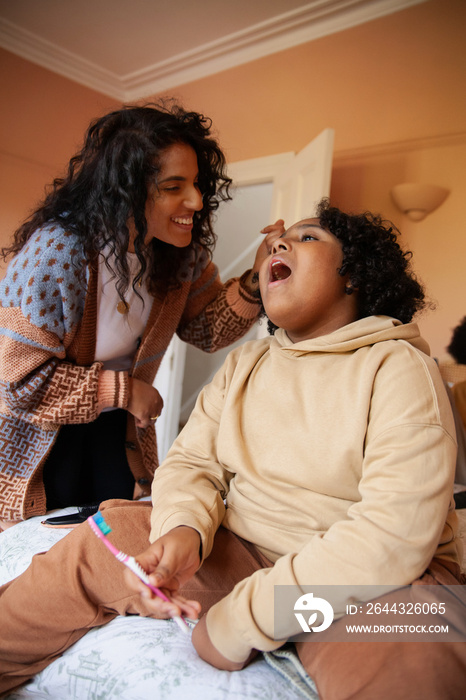 Mid-sized mother helping her son brush his teeth