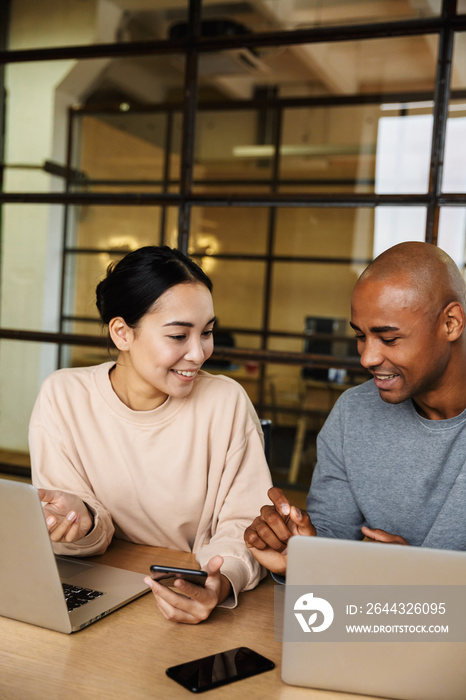 Image of multiethnic young coworkers working on laptops in office