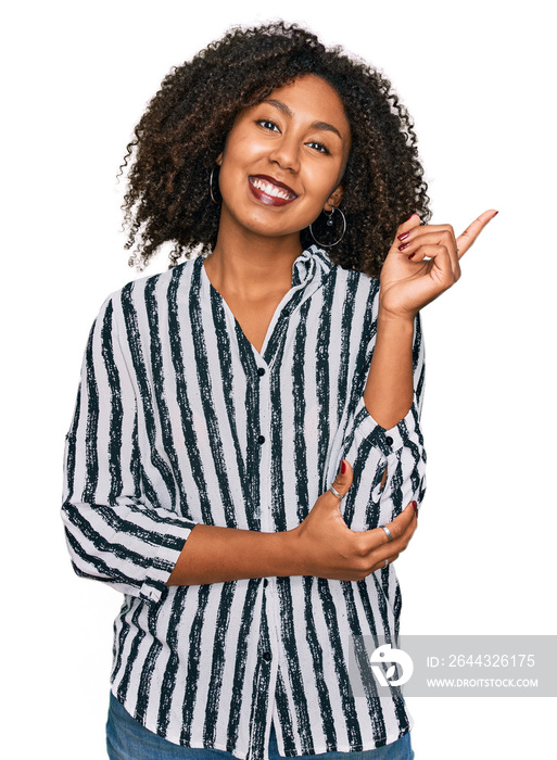 Young african american girl wearing casual clothes with a big smile on face, pointing with hand and finger to the side looking at the camera.