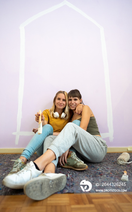 Portrait of happy gay couple with relax under paint home roof celebrate relocation to own house.