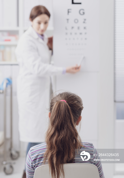 Oculist testing a young patient’s eyesight using an eye chart