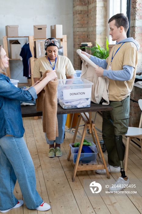 Group of young females and man choosing donation clothes