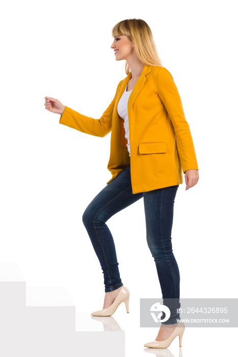 Young Woman In Yellow Jacket And High Heels Is Walking Up The Stairs. Side View.