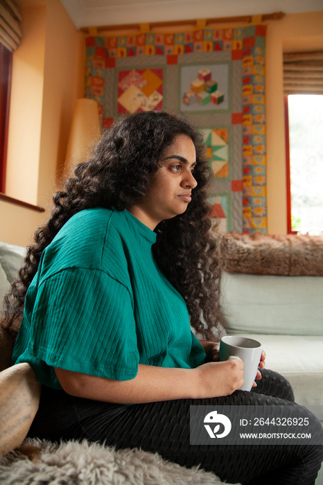 Curvy Indian girl with Cerebral Palsy drinking coffee in the living room