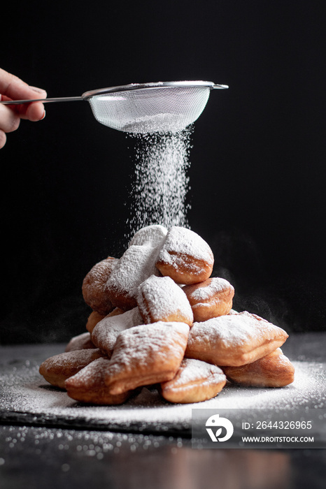 Stacked beignets with powdered sugar on black backround