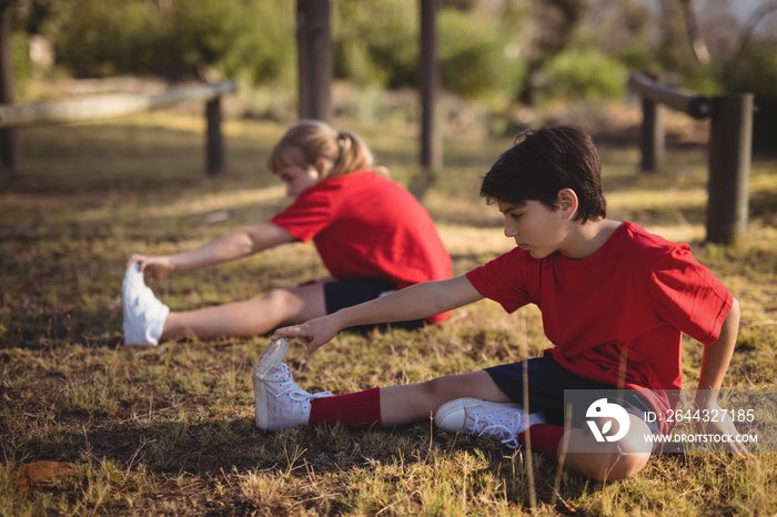 Kids performing stretching exercise during obstacle course