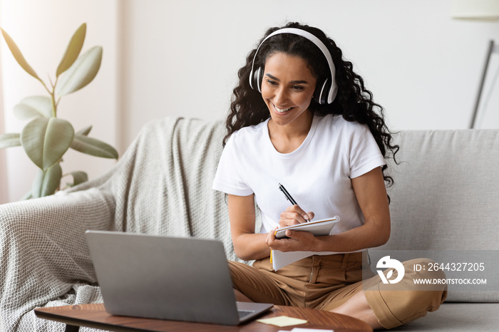 Cheerful lady attending webinar, using laptop and wireless headset