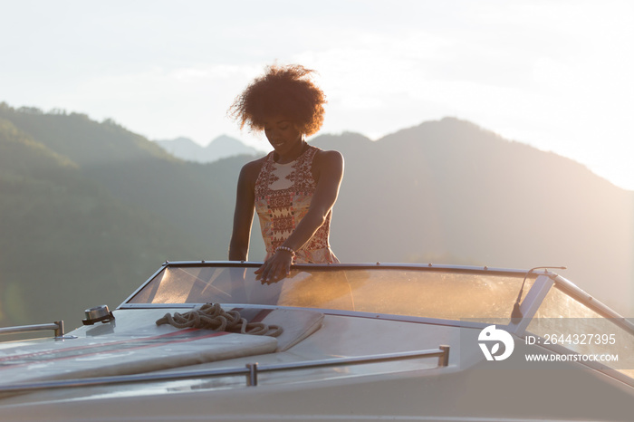 Summer vacation - young afro woman driving a motor boat on sunse