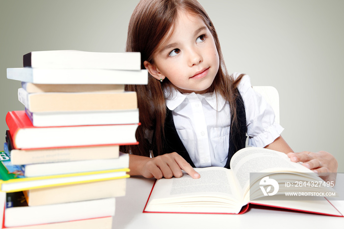 Young cute girl sitting at the table and reading a book