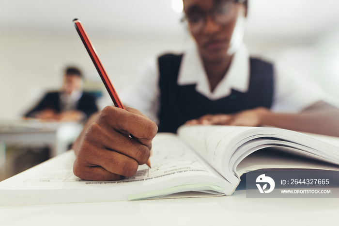 Female student writing in book during class