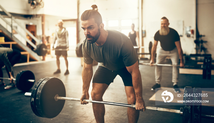 Fit young man lifting weights in a gym class