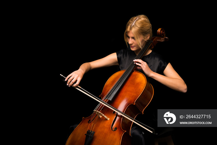 Young girl playing the cello on isolated black background