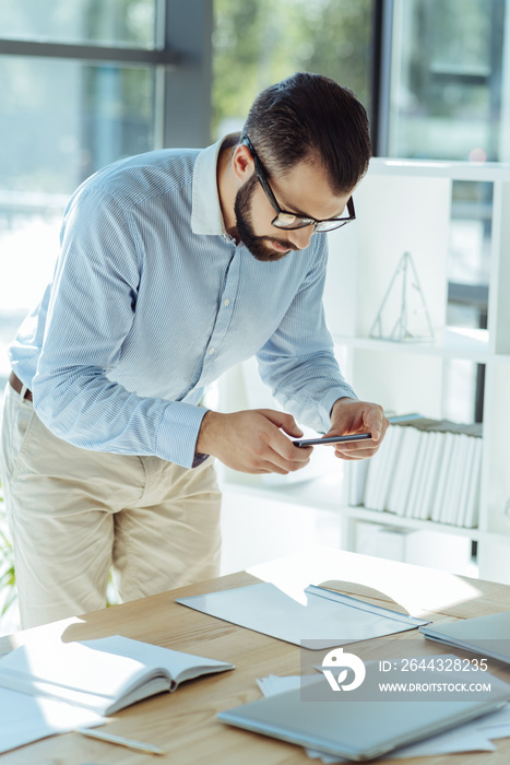 Young office worker taking photos of documents