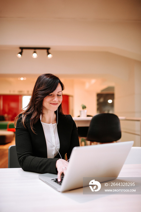 Happy businesswoman in headphones communicating online by video call.