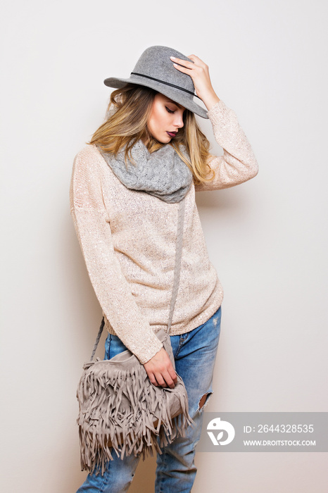 Beautiful modern young woman in autumn casual outfit. Studio portrait of gorgeous blonde teenage girl in neutral toned clothes and accessories.