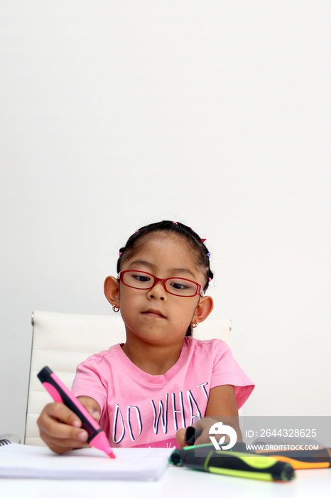 4-year-old brunette Latina girl with autism spectrum disorder ASD like Asperger, Rett and Heller draws at a desk, plays with colors alone antisocial