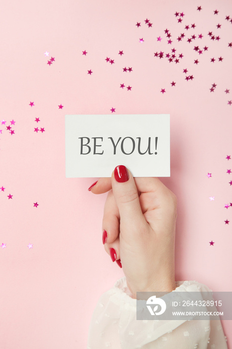 Woman holding card with Be You motivational quote.