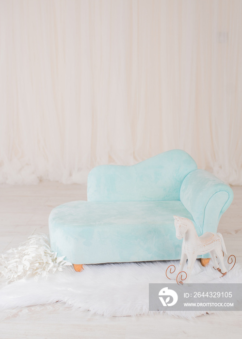 Couch with a rocking horse for a baby photo session in a photo studio