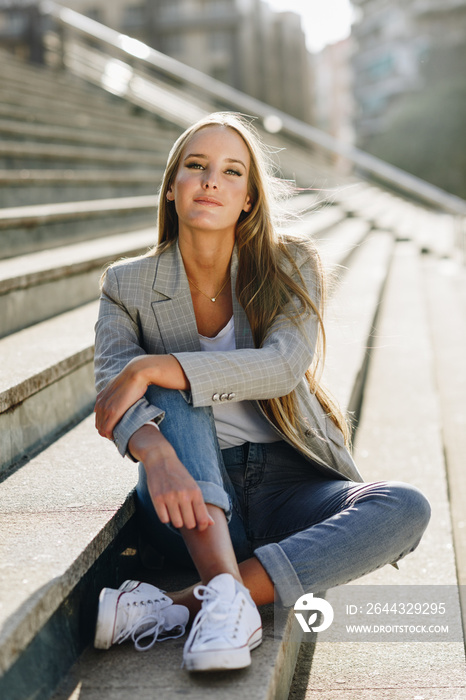 Beautiful young blonde woman sitting on urban steps.