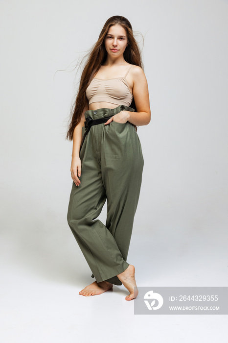 Portrait of young pretty girl with long hair posing isolated over gray studio background. Wellness, wellbeing, bodypositive, fashion concept.