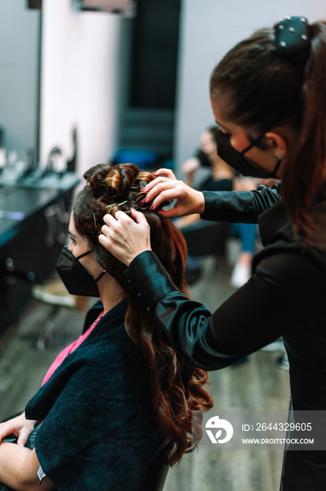 woman wearing face mask getting her hair done at local hairdresser beauty salon.